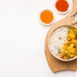 Aloo gobi Indian vegetarian vegetable dish on a wooden chopping board. Copy space