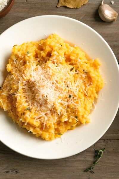 Pumpkin Risotto with herbs and parmesan cheese on wooden