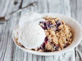 Blackberry and Blueberry Cobbler topped with a golden oatmeal crisp with ice cream. Extreme selective focus with blurred background.
