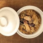 Clay pot chicken rice with mushroom in clay ceramic bowl on rustic wood table background