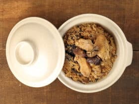Clay pot chicken rice with mushroom in clay ceramic bowl on rustic wood table background
