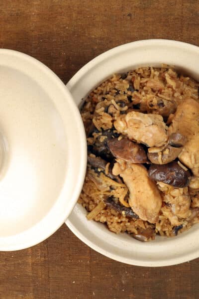 Clay pot chicken rice with mushroom in clay ceramic bowl on rustic wood table background
