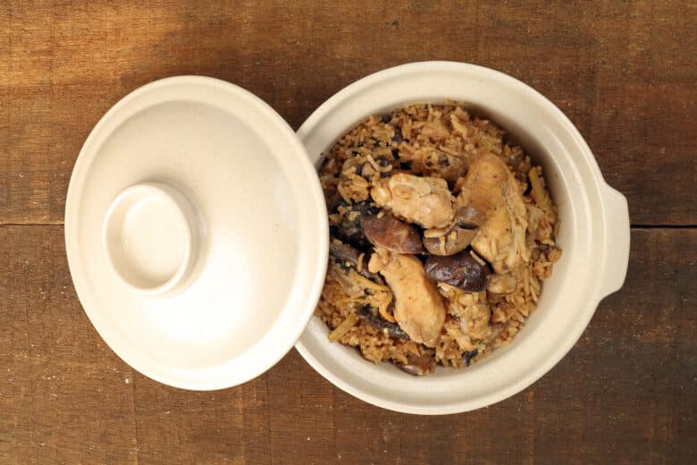 Clay pot chicken rice with mushroom in clay ceramic bowl on rustic wood table background