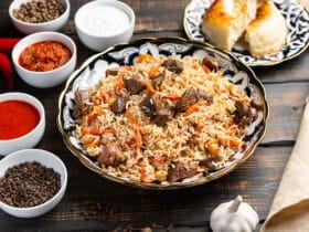 Uzbek plov a rice dish prepared with beef, stewed with fried onions, garlic and carrots rice, dried fruits, garlic and cumin.