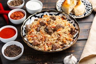 Uzbek plov a rice dish prepared with beef, stewed with fried onions, garlic and carrots rice, dried fruits, garlic and cumin.