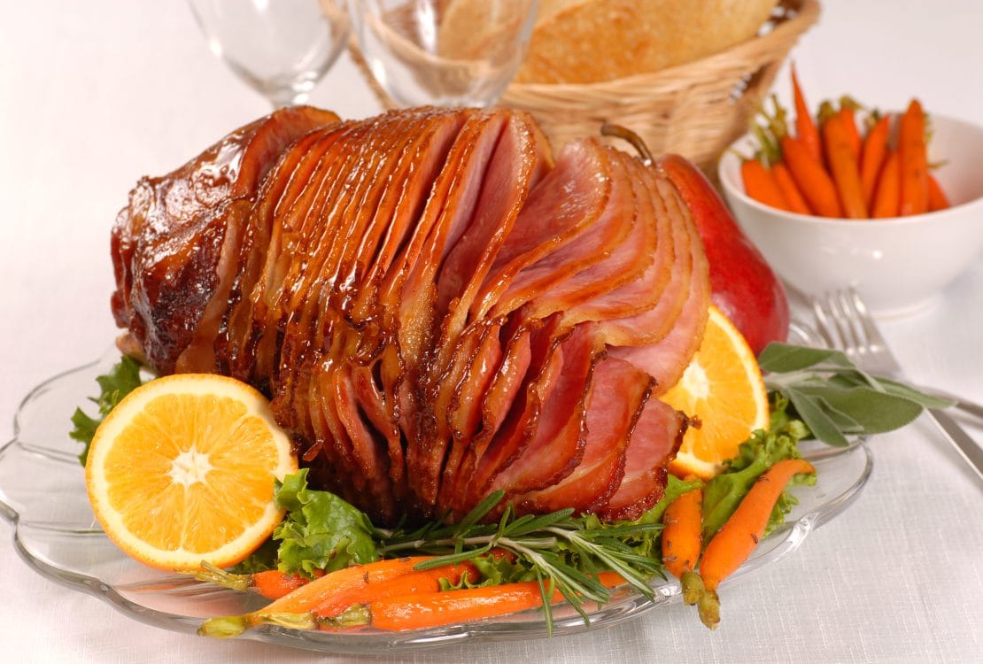 Brown sugar and honey glazed ham with carrots, herbs, fruit and bread